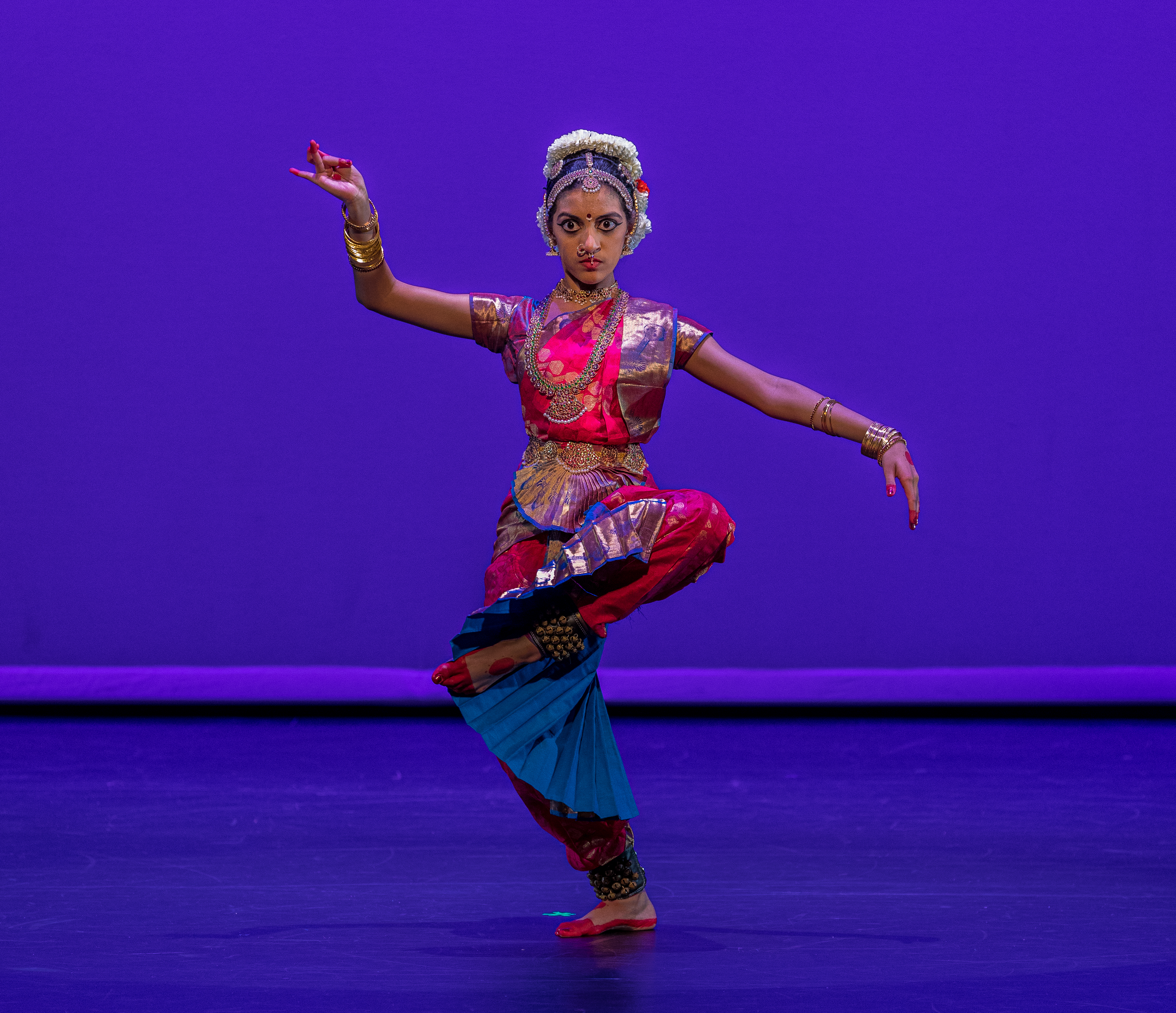 Aarushi Lakhi in a pink and blue Bharatanatyam costume with her left leg lifted