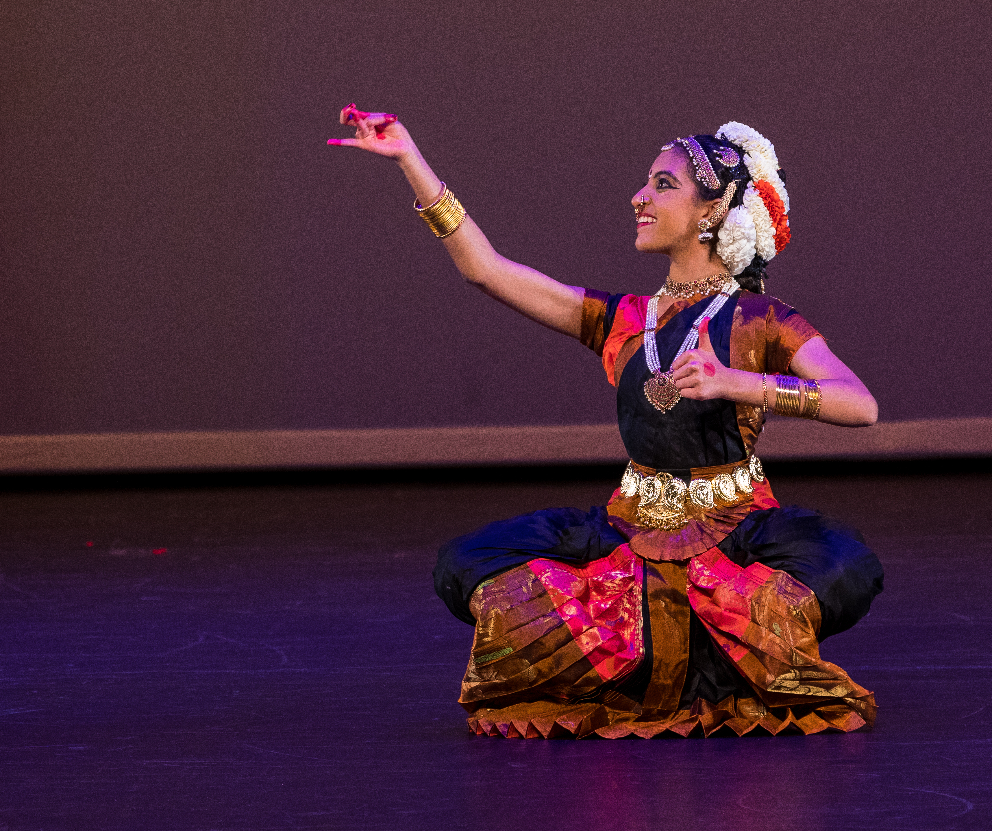 Aarushi Lakhi in a black and pink Bharatanatyam costume showing a bell and plate